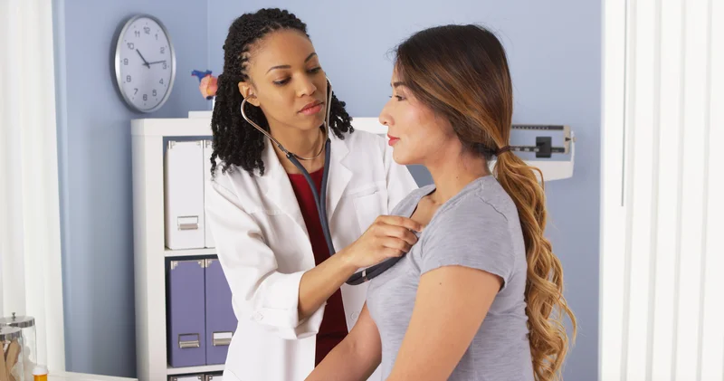 A doctor listens to a woman's heart